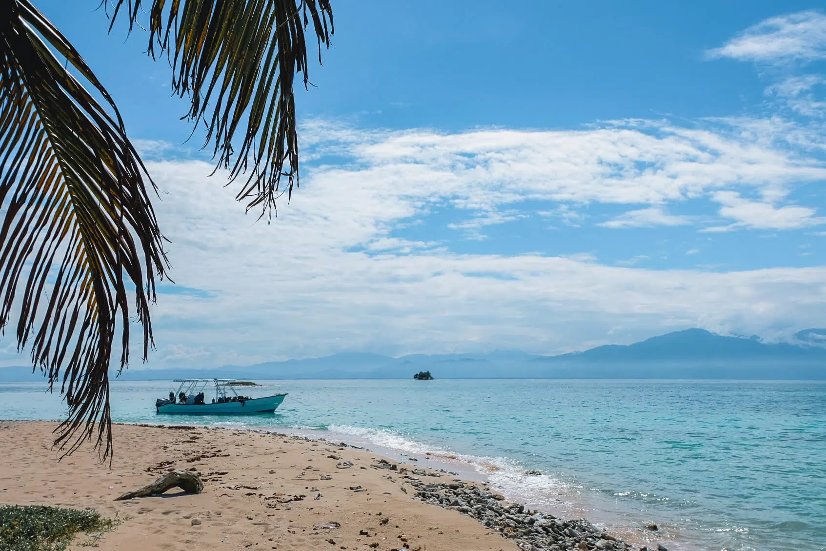 A beach in Cayos Cochinos with the mountains of Northern Honduras