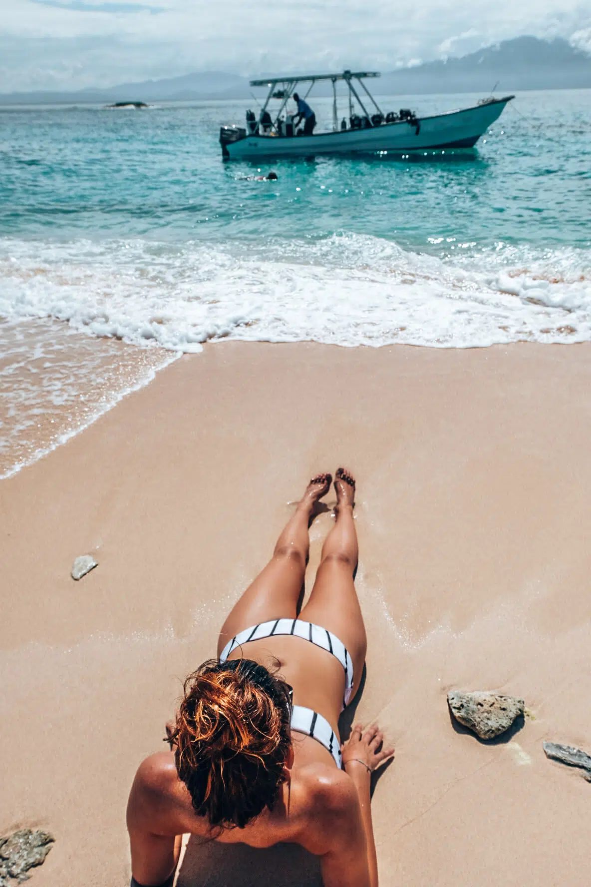 Girl laying on the beach at Chachahuate Cay, Cayos Cochinos