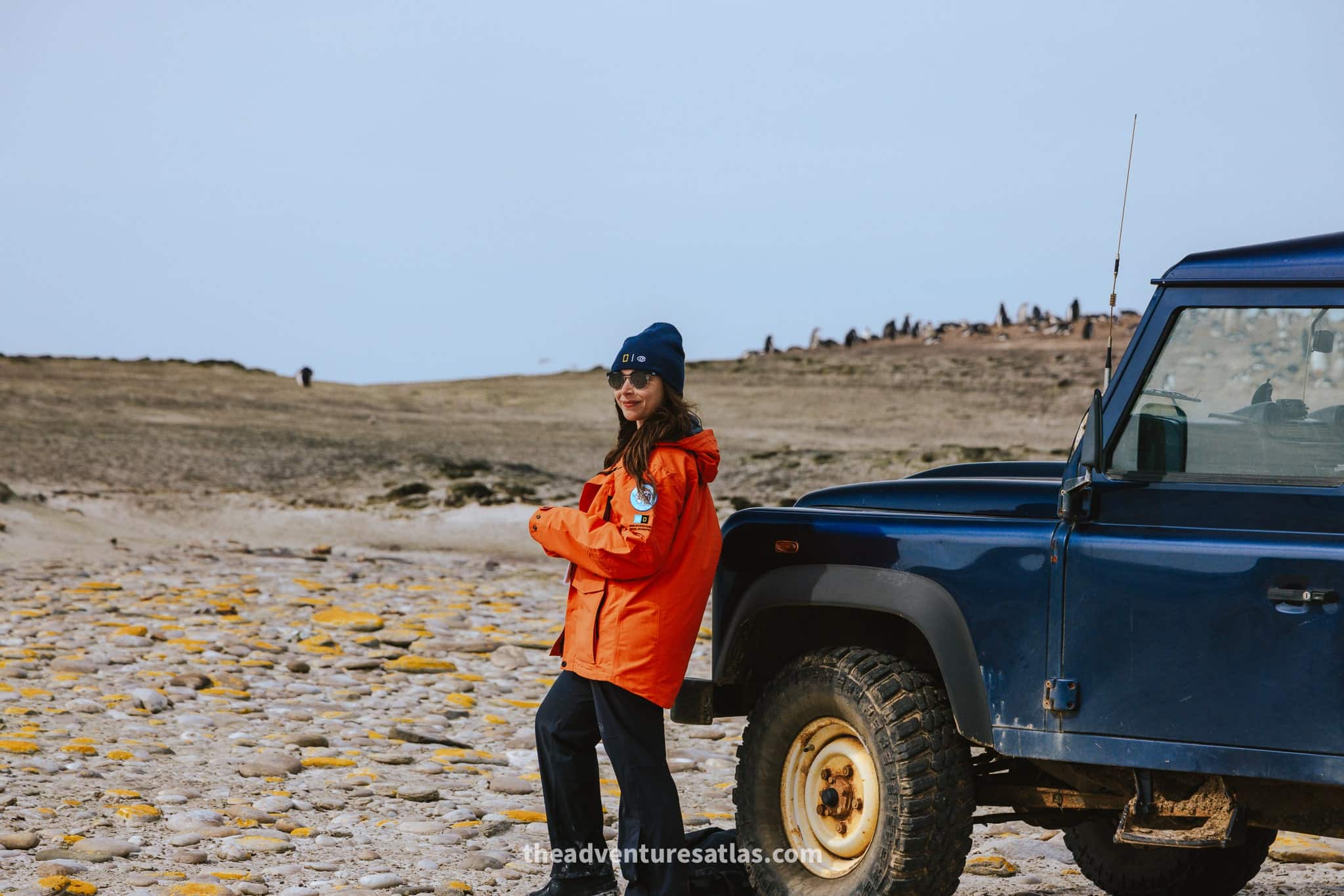 woman in an orange parka standing in front of a land cruiser on Saunders Island in the Falkland Islands