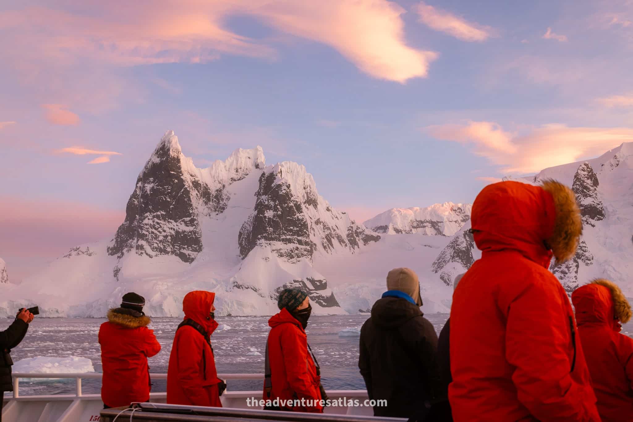 Passengers wearing parkas on an Antarctica cruise at sunset